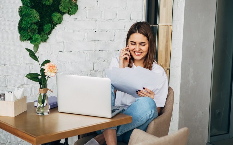 Młoda kobieta z laptopem rozmawia przez telefon